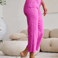 Woman wearing Crop Chloe full-size tummy control high waist raw hem RFM jeans in pink with white top and heels.