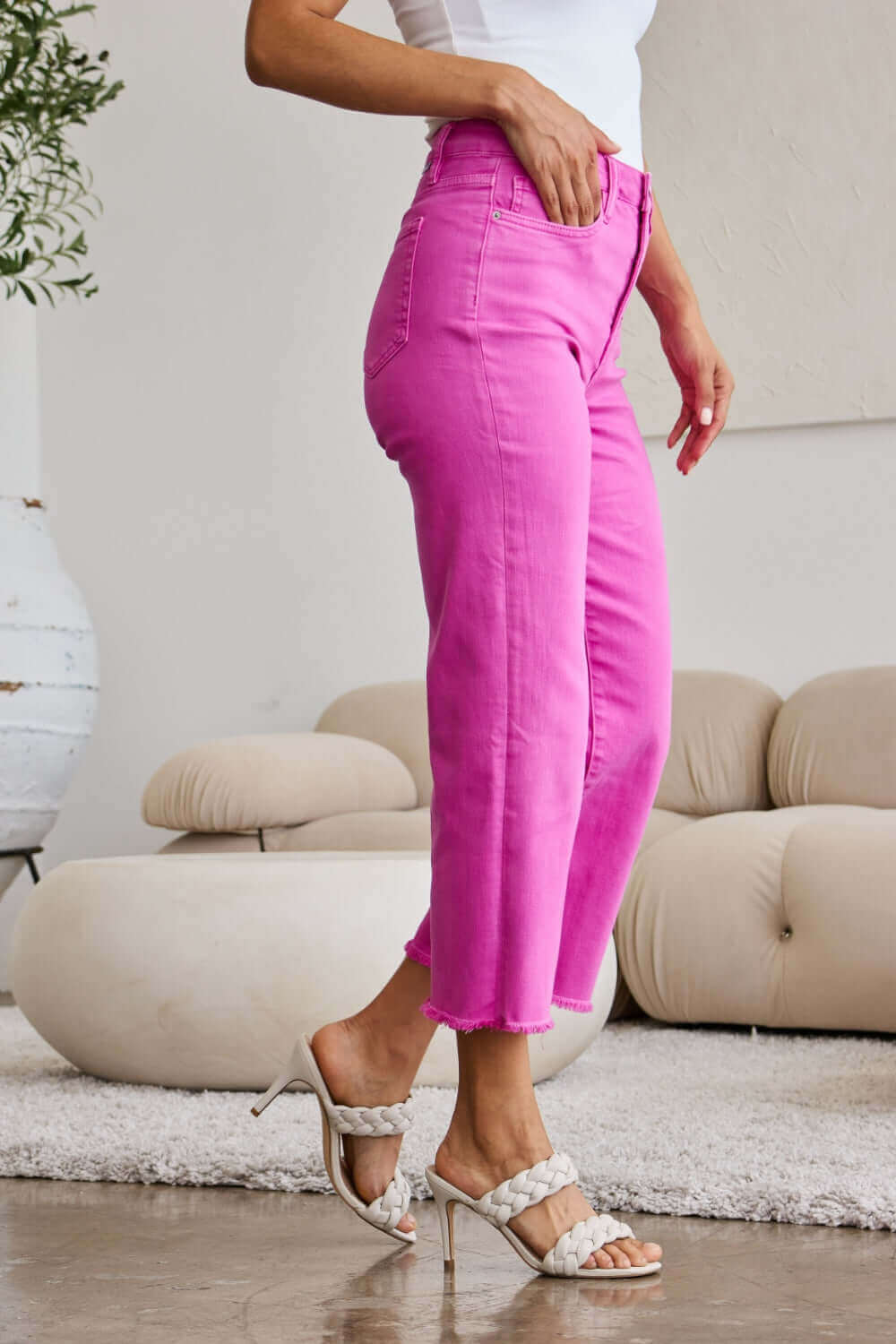 Woman wearing Crop Chloe full-size tummy control high waist raw hem RFM jeans in pink with white top and heels.