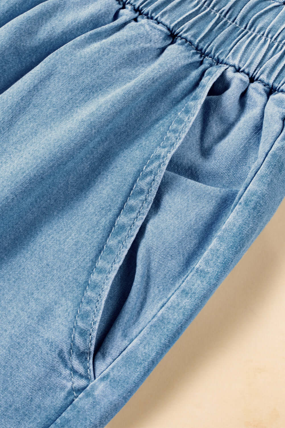 Close-up of light wash denim with drawstring waist and spacious cargo pocket detail. Perfect blend of comfort and style!