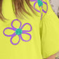 Bright yellow t-shirt with purple and teal flower embroidery detail, showcasing the stylish floral design.