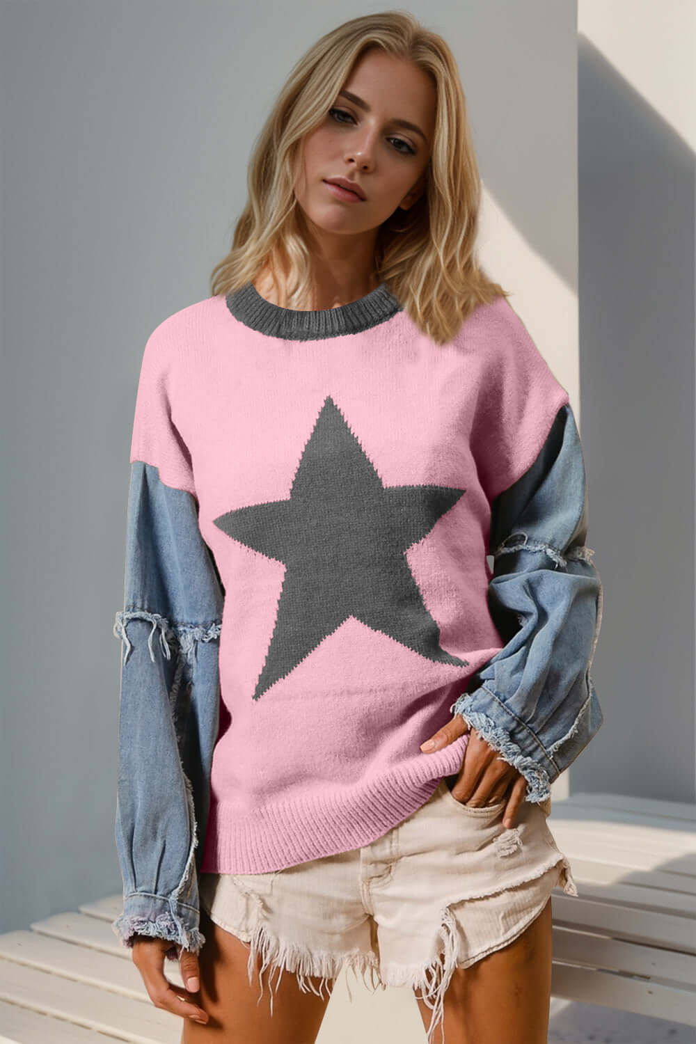 Woman in pink star pattern sweater with denim sleeves, standing outdoors.