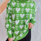 Woman wearing Bella Road Heart Contrast Long Sleeve Dropped Shoulder Sweater in green with white heart pattern.