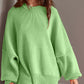 Woman wearing a green Double Take Side Slit Round Neck Long Sleeve Sweater with a playful side slit design.