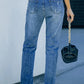 Back view of woman wearing Pumpkin Distressed Straight Jeans with slightly stretchy denim and distressed details.