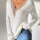 Stylish openwork V-neck long sleeve sweater paired with jeans, showcasing a cozy and fashionable casual look.