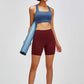 Model showing off Millennia high waist training shorts and sports bra, ready for gym workouts with yoga mat.