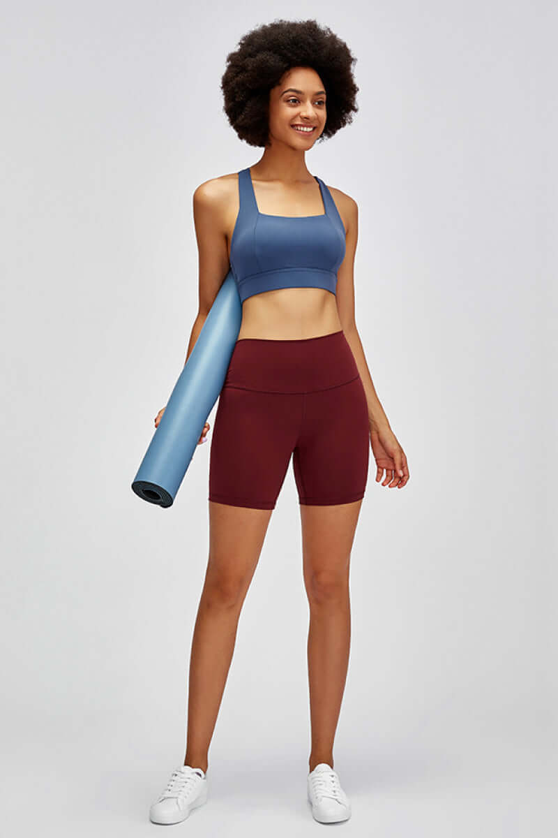 Model showing off Millennia high waist training shorts and sports bra, ready for gym workouts with yoga mat.