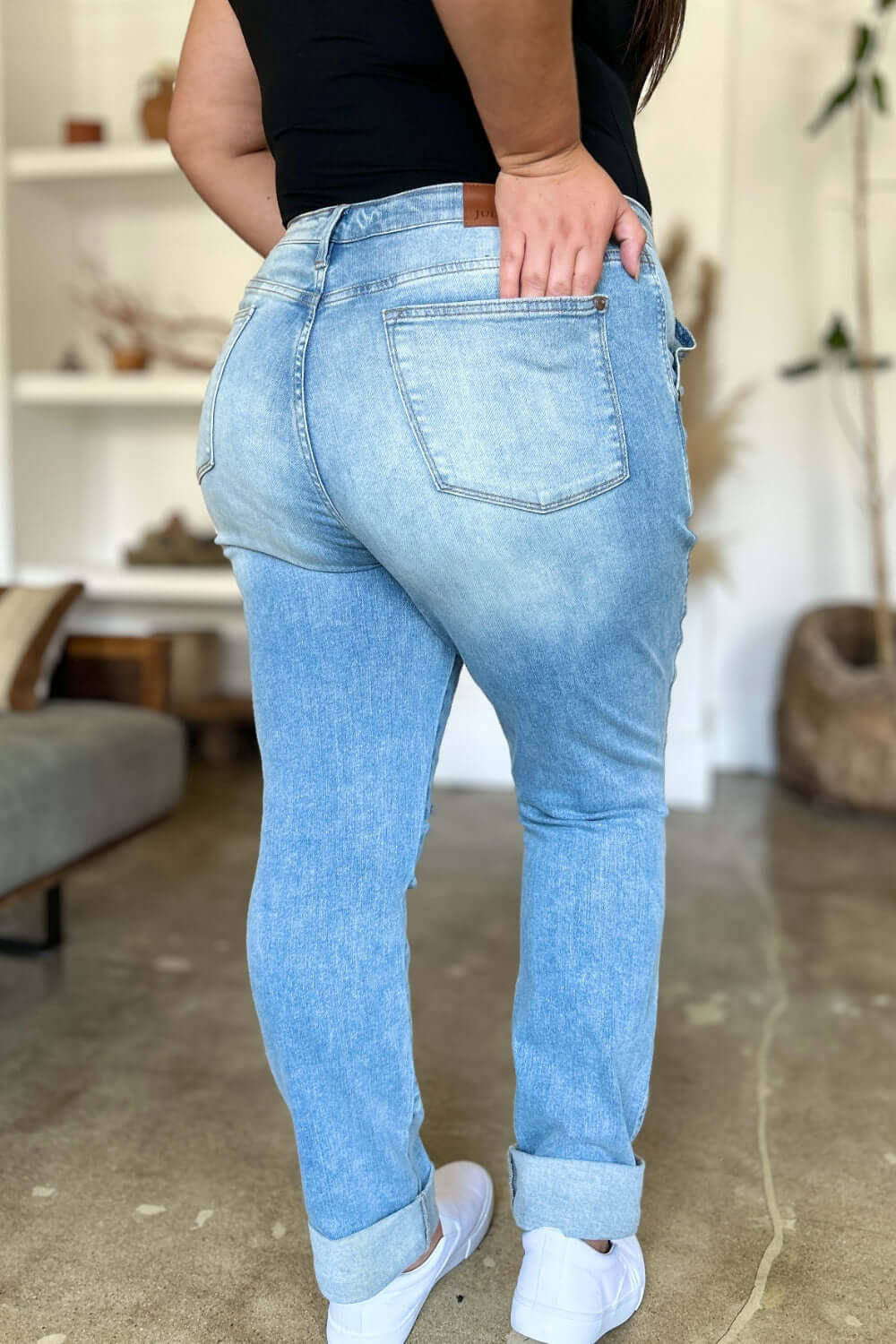 Woman wearing Judy Blue distressed straight jeans with patch pockets, showcasing the back view and light wash detailing.