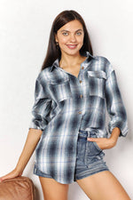 Woman wearing plaid dropped shoulder shirt with a collared neckline and long sleeves, paired with denim shorts.