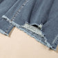 Close-up of distressed raw hem on bootcut jeans, showcasing slightly stretchy denim fabric with a stylish frayed edge.