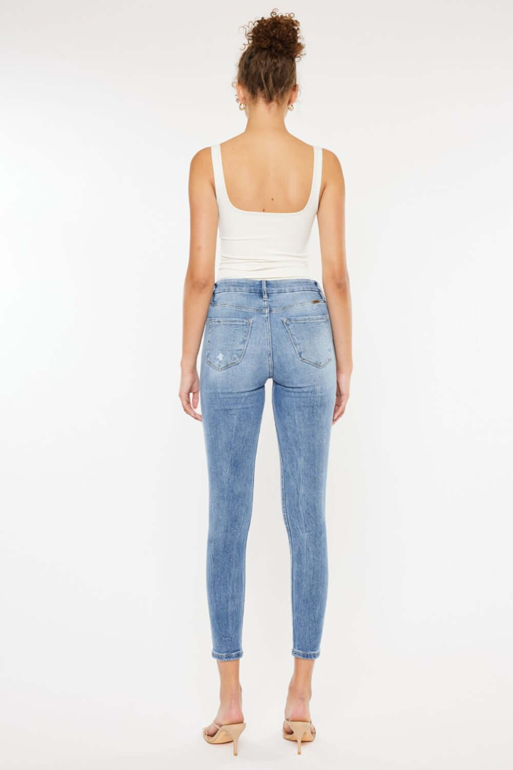 Back view of model wearing High Waist Cat's Whiskers Skinny Jeans with a white tank top.