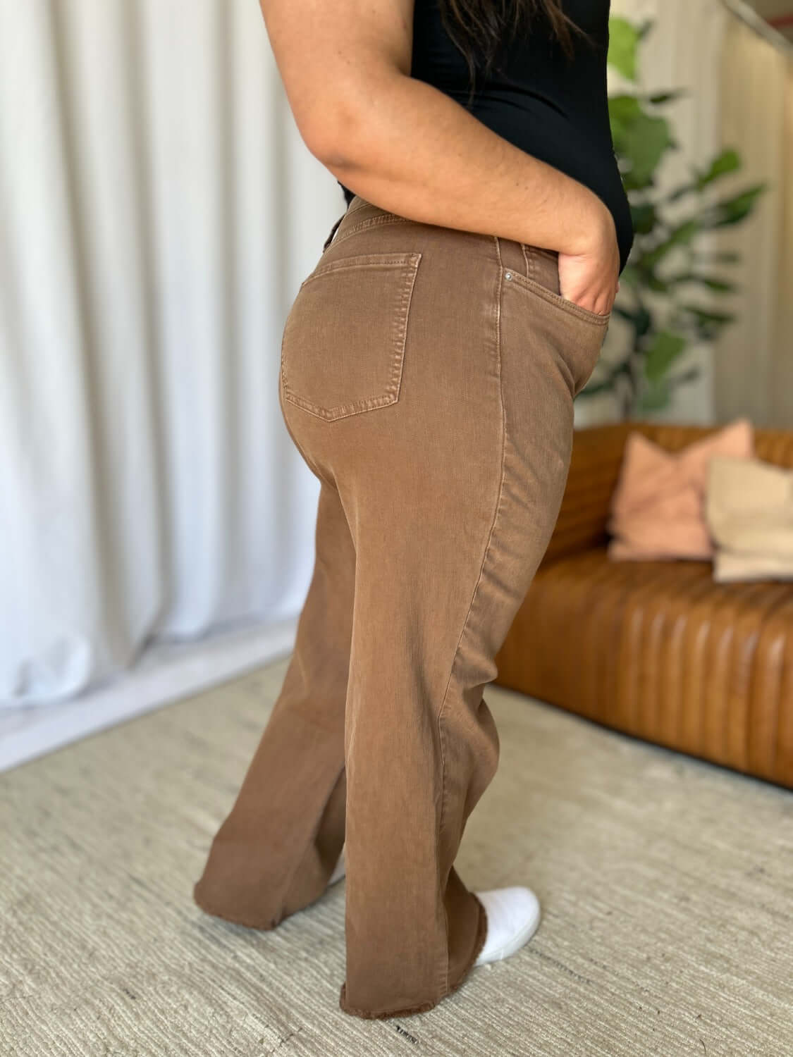 Woman wearing RFM Full Size High Rise Garment Dye Wide Leg Jeans in brown, showcasing the high-waist fit and relaxed wide-leg silhouette