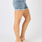 Woman wearing Button Fly Raw Hem Denim Shorts from Judy Blue Jeans, showcasing side view and stylish hem detailing.