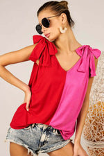 Stylish woman wearing a Shoulder Ribbon Tied Contrast Tank in red and pink with ribbon tie details on the shoulders, paired with denim shorts.