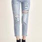 Woman wearing distressed slim cropped jeans with ripped detailing and black ankle boots.