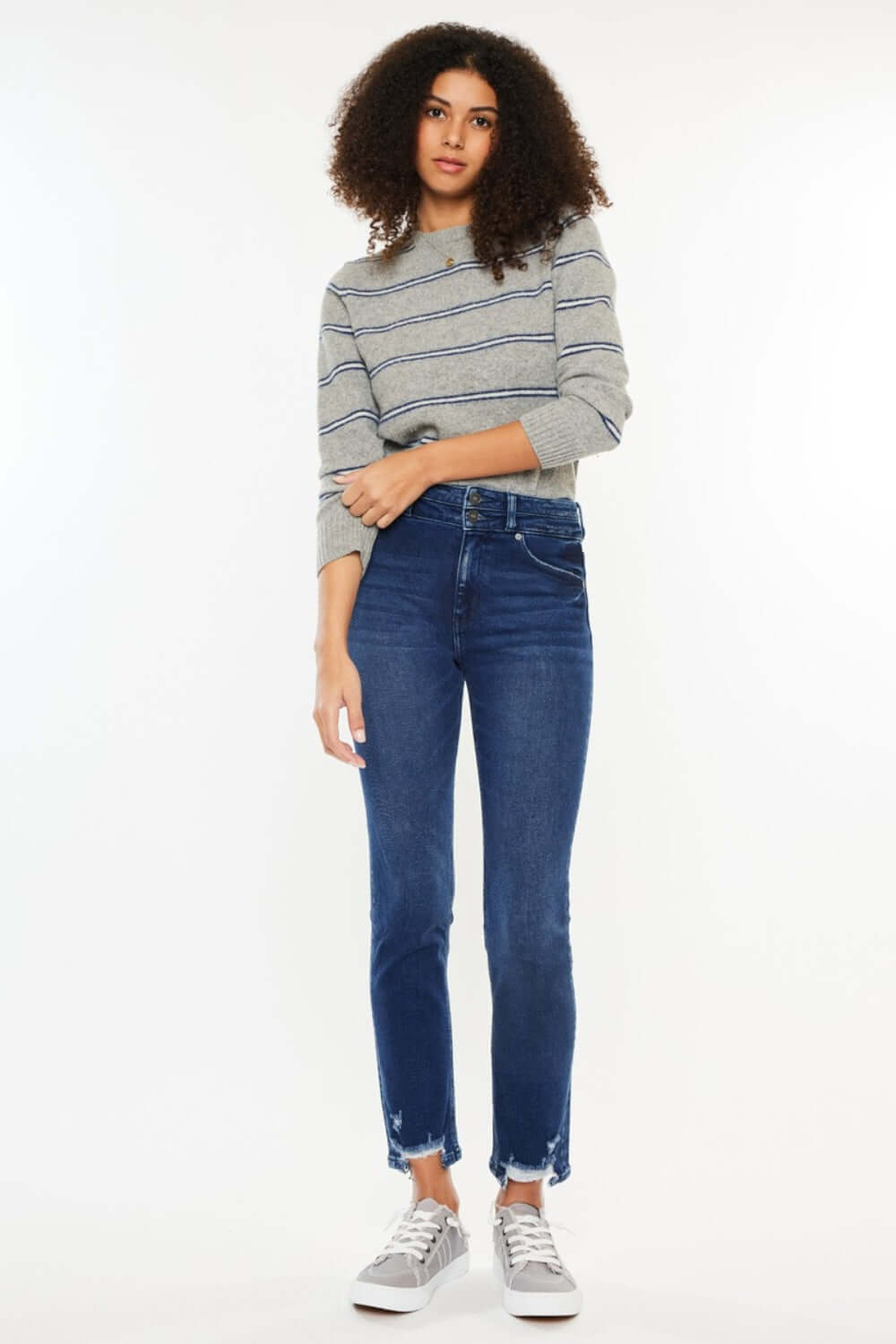 Model wearing High Rise Slim Straight Jeans with a grey striped sweater and sneakers, showcasing a stylish and comfortable outfit.