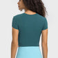 Back view of Millennia Round Neck Cropped Sports T-Shirt in teal, perfect for yoga and stylish workouts.