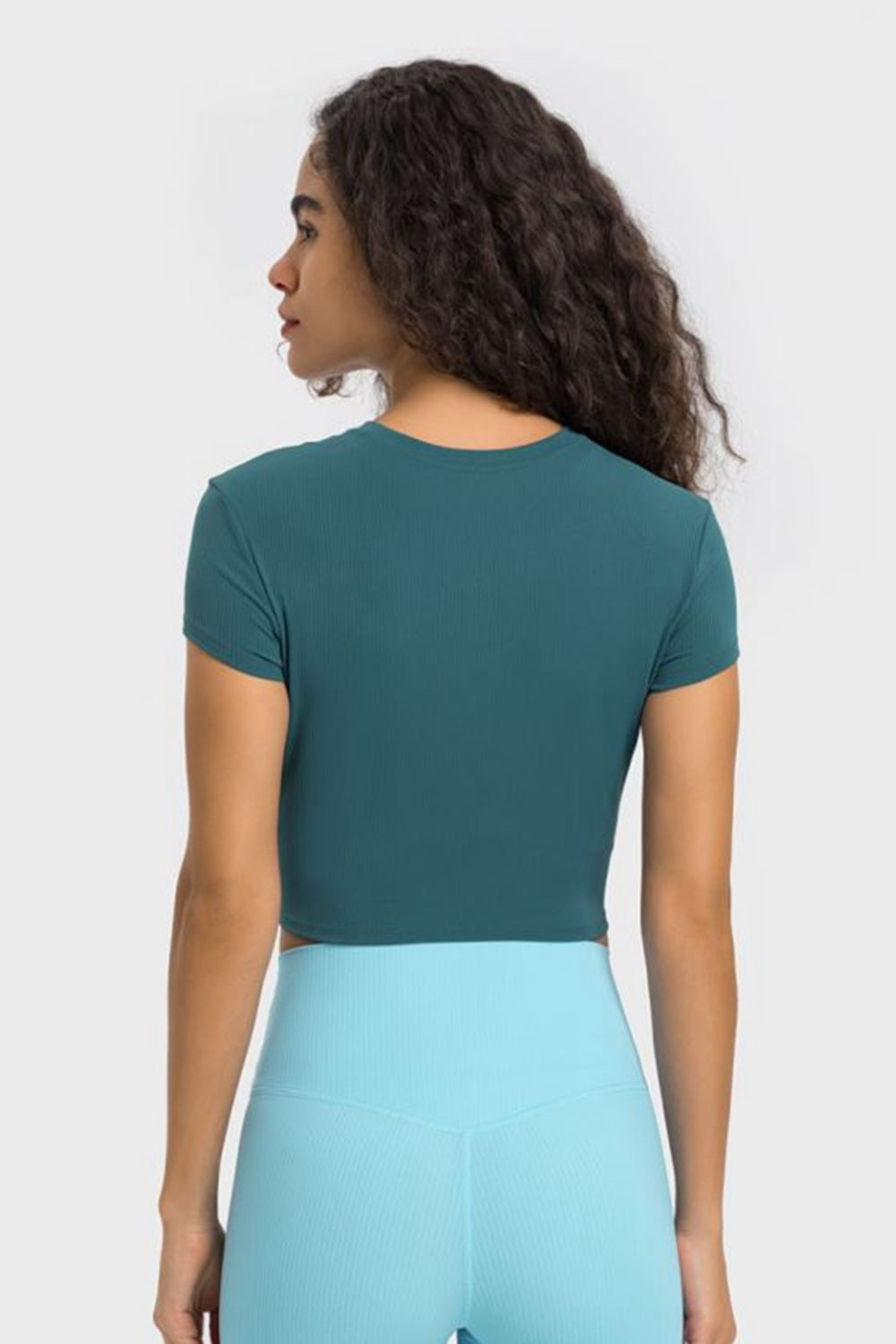 Back view of Millennia Round Neck Cropped Sports T-Shirt in teal, perfect for yoga and stylish workouts.