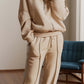 Woman wearing Bella Road Zip Up Long Sleeve Top and Pants Set in beige standing in a room.