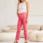 Woman modeling pink RFM Jeans with high waist and raw hem in a stylish living room setting.