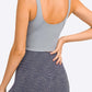 Woman showcasing the back view of a sleek gray crop sports bra, paired with stylish striped leggings.