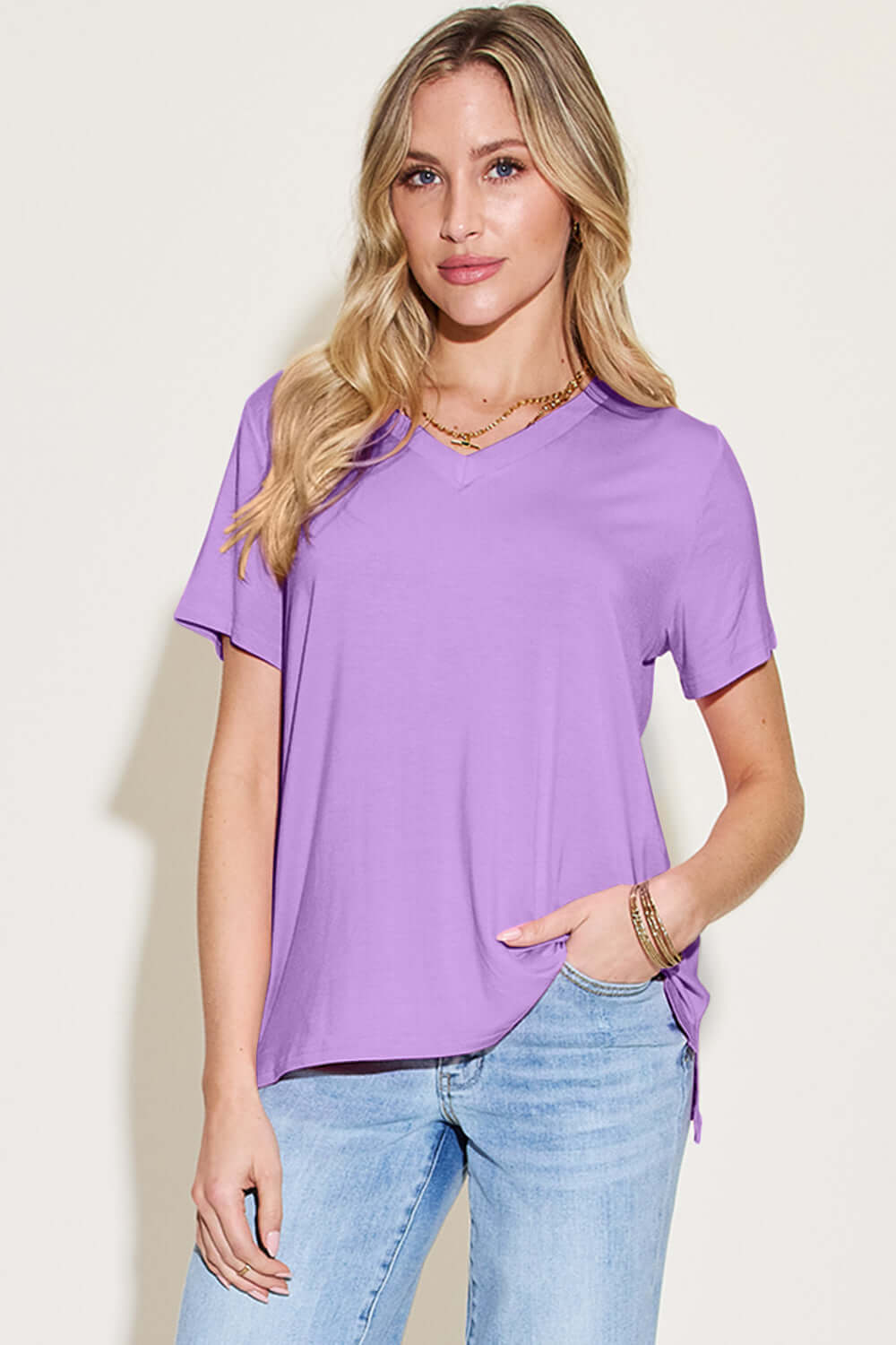 Woman wearing Bamboo V-Neck High-Low T-Shirt in lavender, basic style, slightly stretchy, made of bamboo and spandex, with light wash jeans.