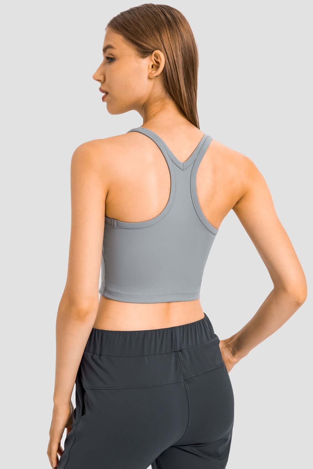 Stylish woman showcasing the Millennia Racerback Sports Bra from the back, featuring a sleek design and comfortable fit.