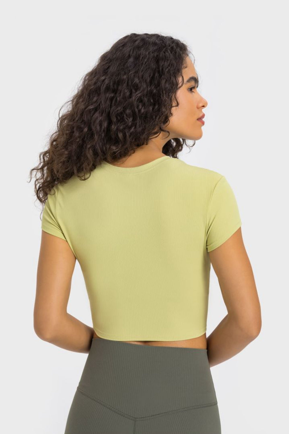 Model showcasing the Millennia cropped sports t-shirt in soft green, perfect for yoga and stylish workouts.