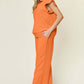 Woman wearing a Texture Ruffle Short Sleeve Top and Drawstring Wide Leg Pants Set in bright orange color with pockets and black sandals