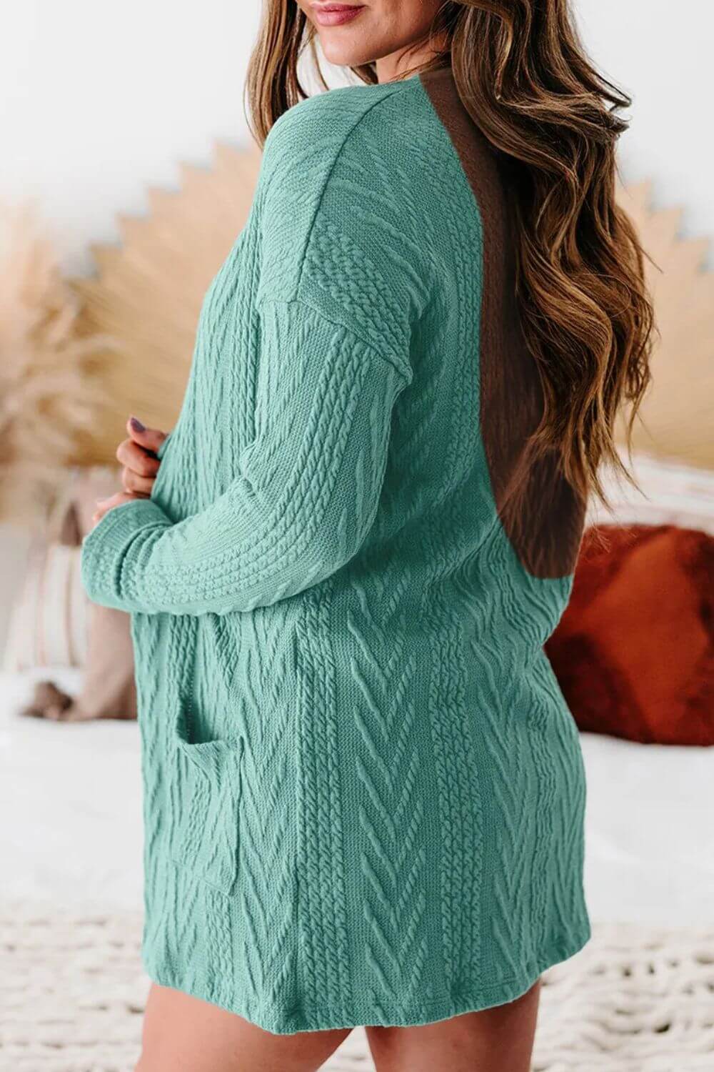 Woman wearing a textured open front cover up with pockets in teal, featuring a slightly stretchy, opaque fabric made of 97% polyester and 3% elastane.