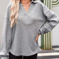 Woman wearing a gray waffle-knit Johnny collar long sleeve sweatshirt with slightly stretchy material.