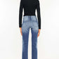 Back view of high waist distressed hem detail cropped straight jeans paired with black top and heels