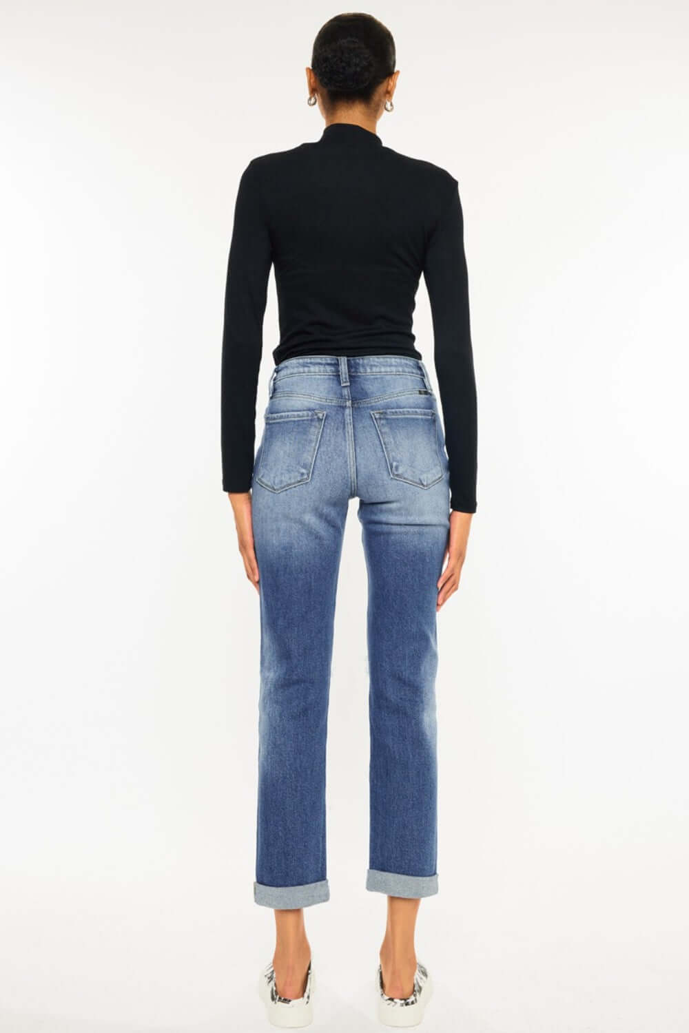 Back view of high waist distressed hem detail cropped straight jeans paired with black top and heels