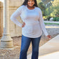 Plus-size model wearing a round neck long sleeve t-shirt with jeans, posing outdoors in a park setting