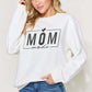 Woman wearing white letter graphic long sleeve sweatshirt with "Mom Mode" text, paired with blue jeans.