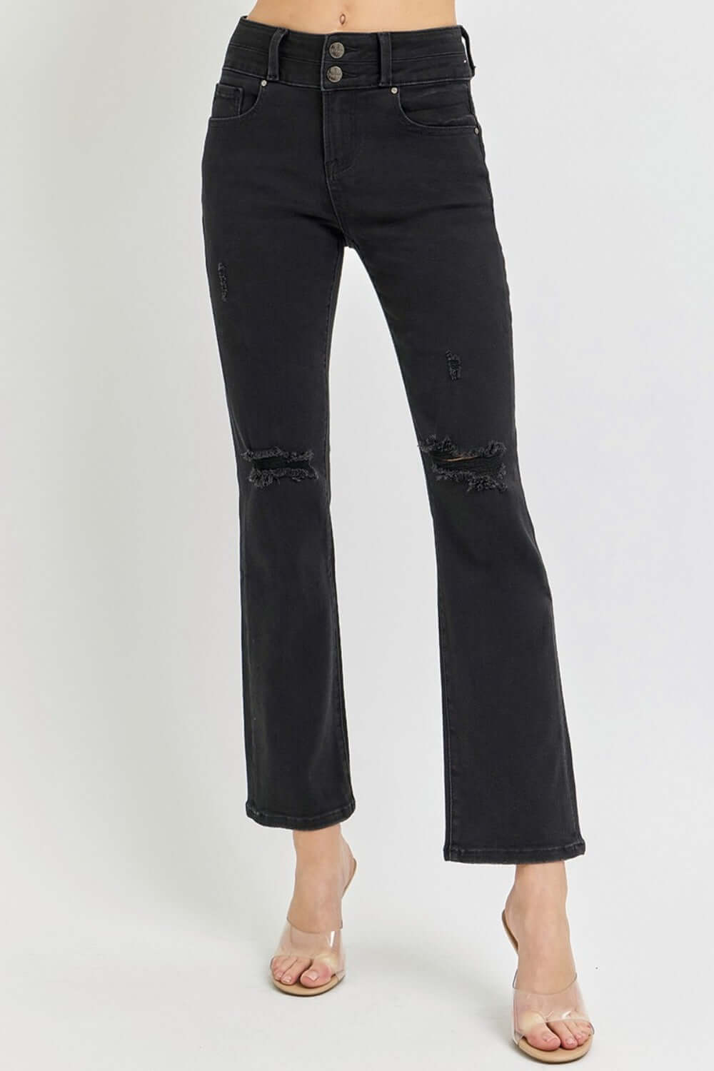 Black high-rise ankle bootcut jeans with wide waistband and distressed knees, styled with heels for a versatile fashion look.