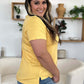 Woman wearing a yellow Bamboo V-Neck High-Low T-Shirt, showcasing side view with slight stretch and comfortable fit.