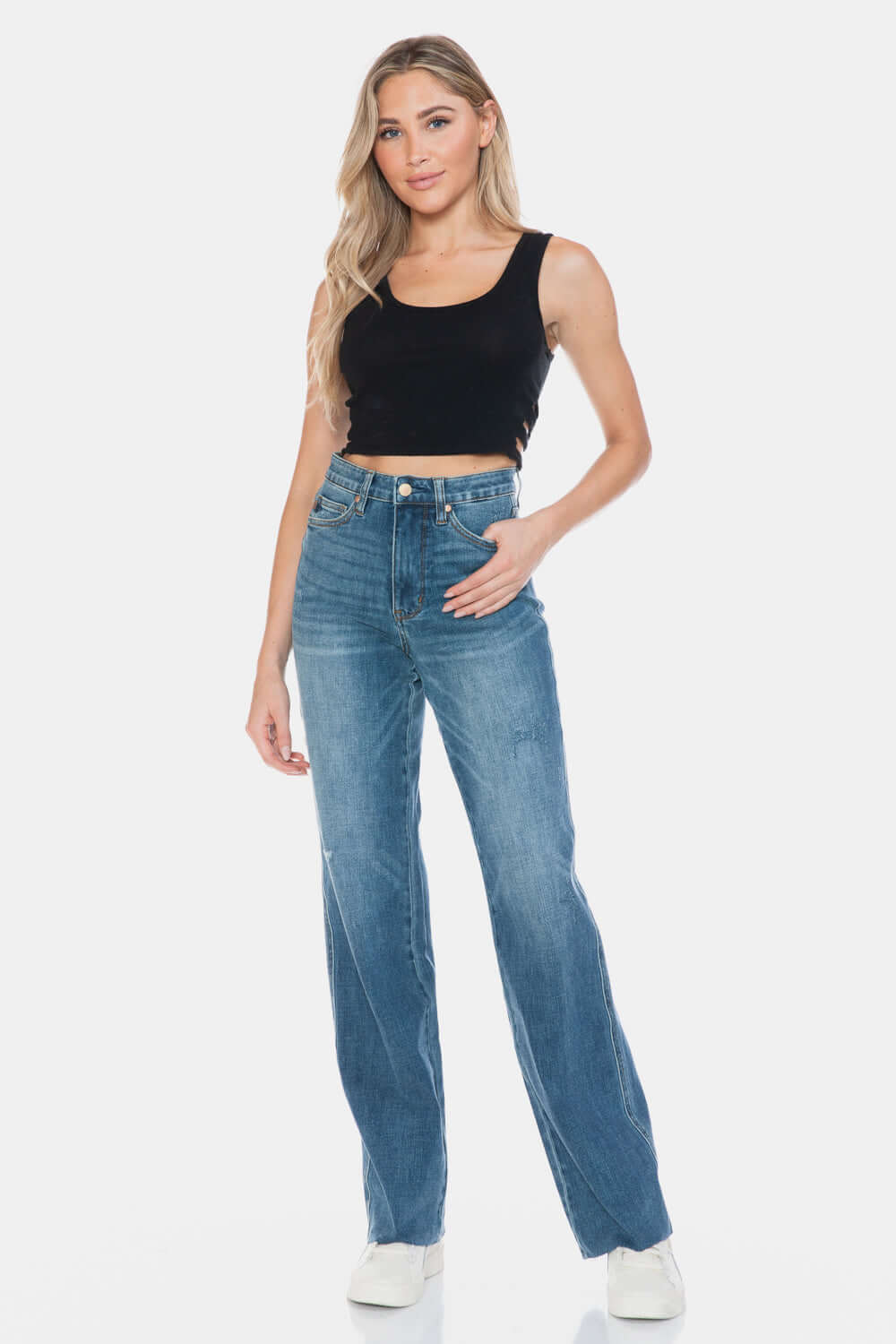 Stylish woman wearing Judy Blue Full Size Tummy Control Cut Raw Hem Straight Jeans with high-waist design and trendy raw hem.