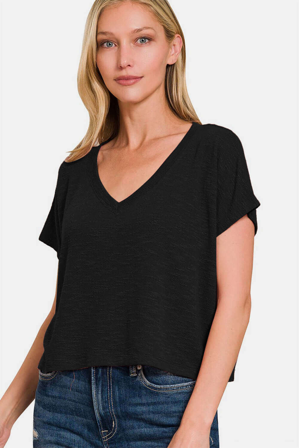 Woman wearing a trendy V-neck short sleeve crop t-shirt in black with jeans, showcasing a stylish and casual fashion look.