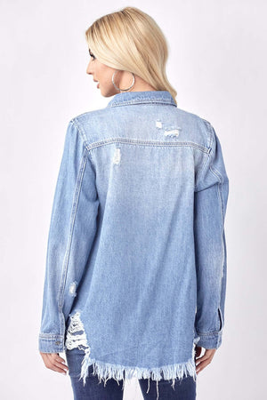 Woman wearing a button-up distressed denim shirt by Risen Jeans, showcasing back view with stylish worn details and frayed hem.