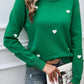 Woman wearing Devine Lace Detail Heart Long Sleeve Sweater in green with white lace hearts, holding a book, and dressed in casual jeans.