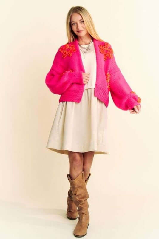 Model showcasing a pink floral applique open front cardigan over a white dress, exuding cozy and stylish vibes.