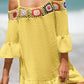 Woman wearing a Crochet Cold Shoulder Three-Quarter Sleeve Cover Up in yellow with ruffled design, featuring multicolored crochet detail, on the beach