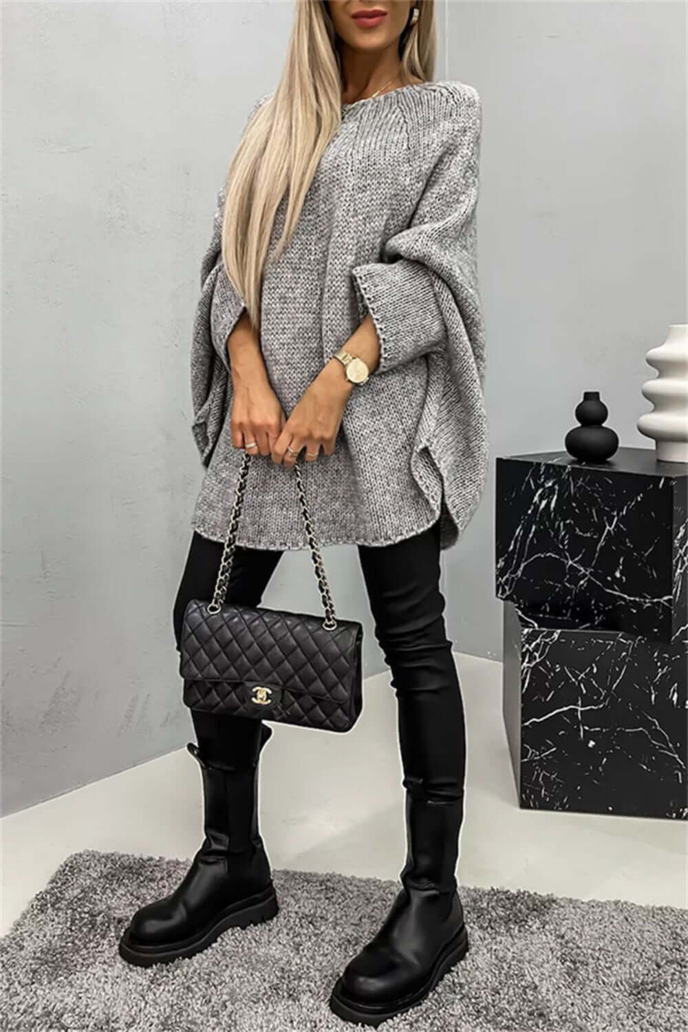 "Model wearing a cozy Bella Road batwing sleeve sweater with black pants and boots, accessorized with a quilted handbag"