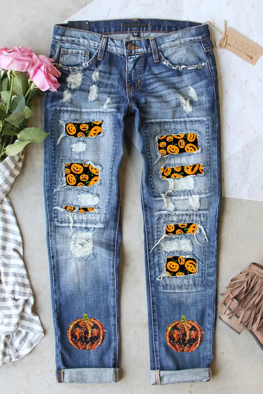 Distressed straight jeans with pumpkin sequin patches, featuring slight stretch for comfort, made of cotton, polyester, and elastane, displayed with flowers.