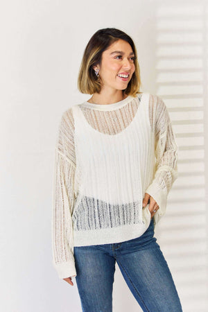 Woman wearing Openwork Ribbed Trim Long Sleeve Knit Top in white, paired with blue jeans, showcasing modern and trendy design.