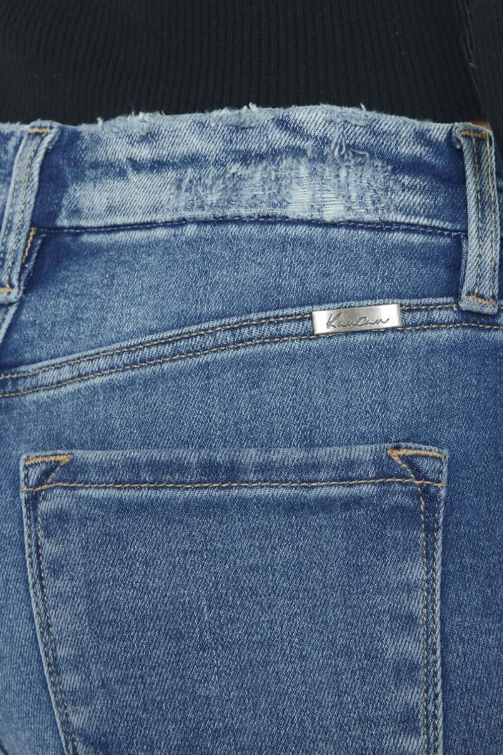 Close-up of Kancan high-rise slim straight jeans with frayed hem and wide waistband in medium stone wash denim.