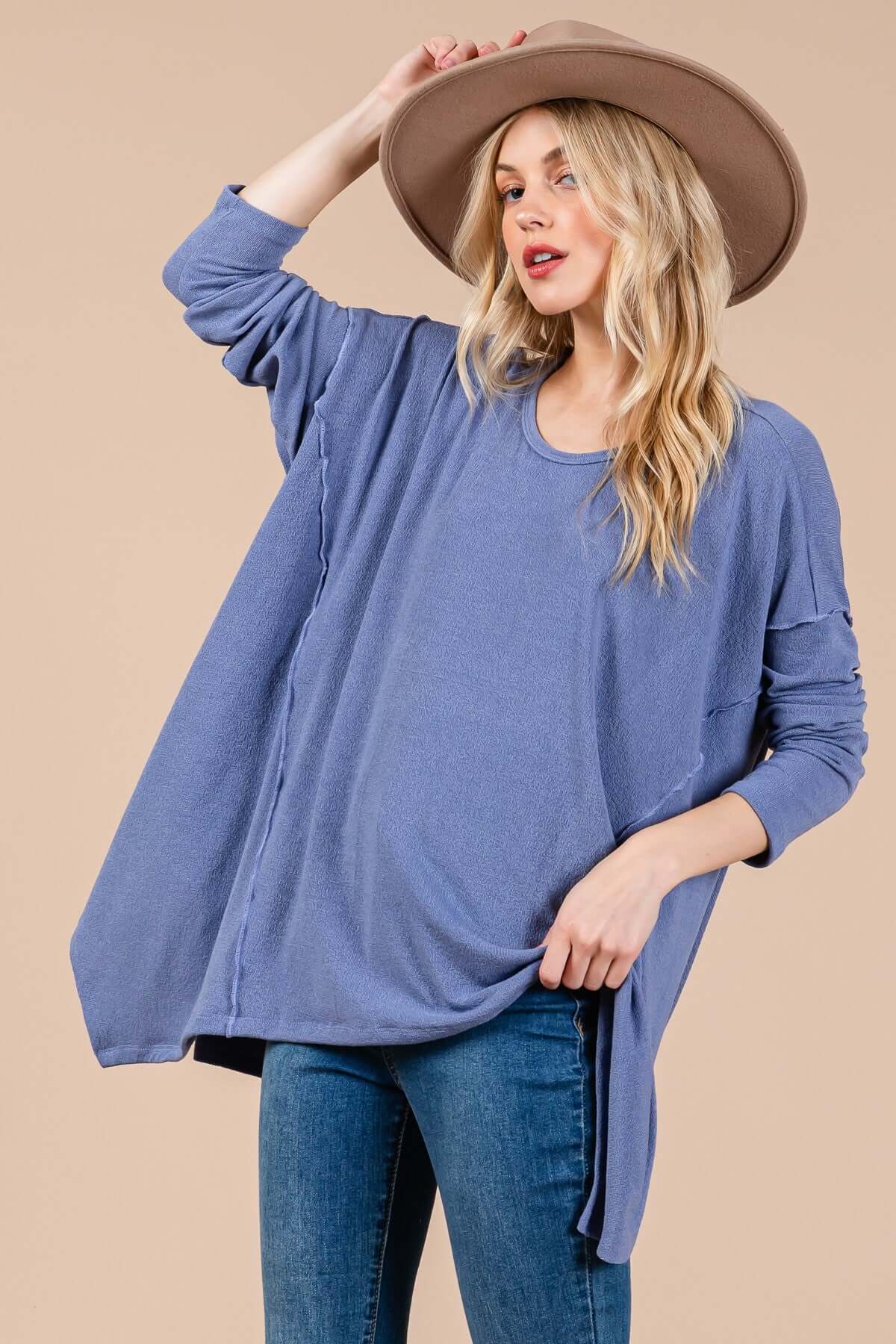 Woman wearing Ces Femme asymmetrical long sleeve top with relaxed fit, soft knit fabric, and hi-low hem, styled with a hat.