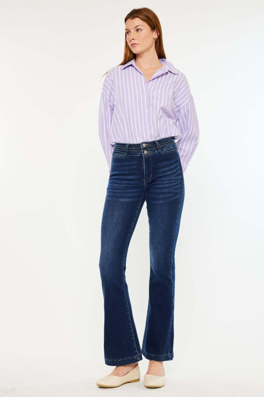 Woman wearing Kancan high-rise double waistband flare jeans in dark wash, showcasing sleek style and flattering fit.