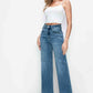 Woman wearing bytos high rise wide leg jeans with pockets, styled with a white crop top and heels for a chic look.